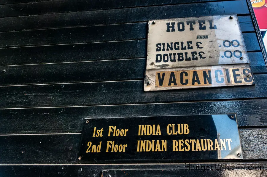 Signs showing India Club, restaurant and hotel vacancies in the same building.